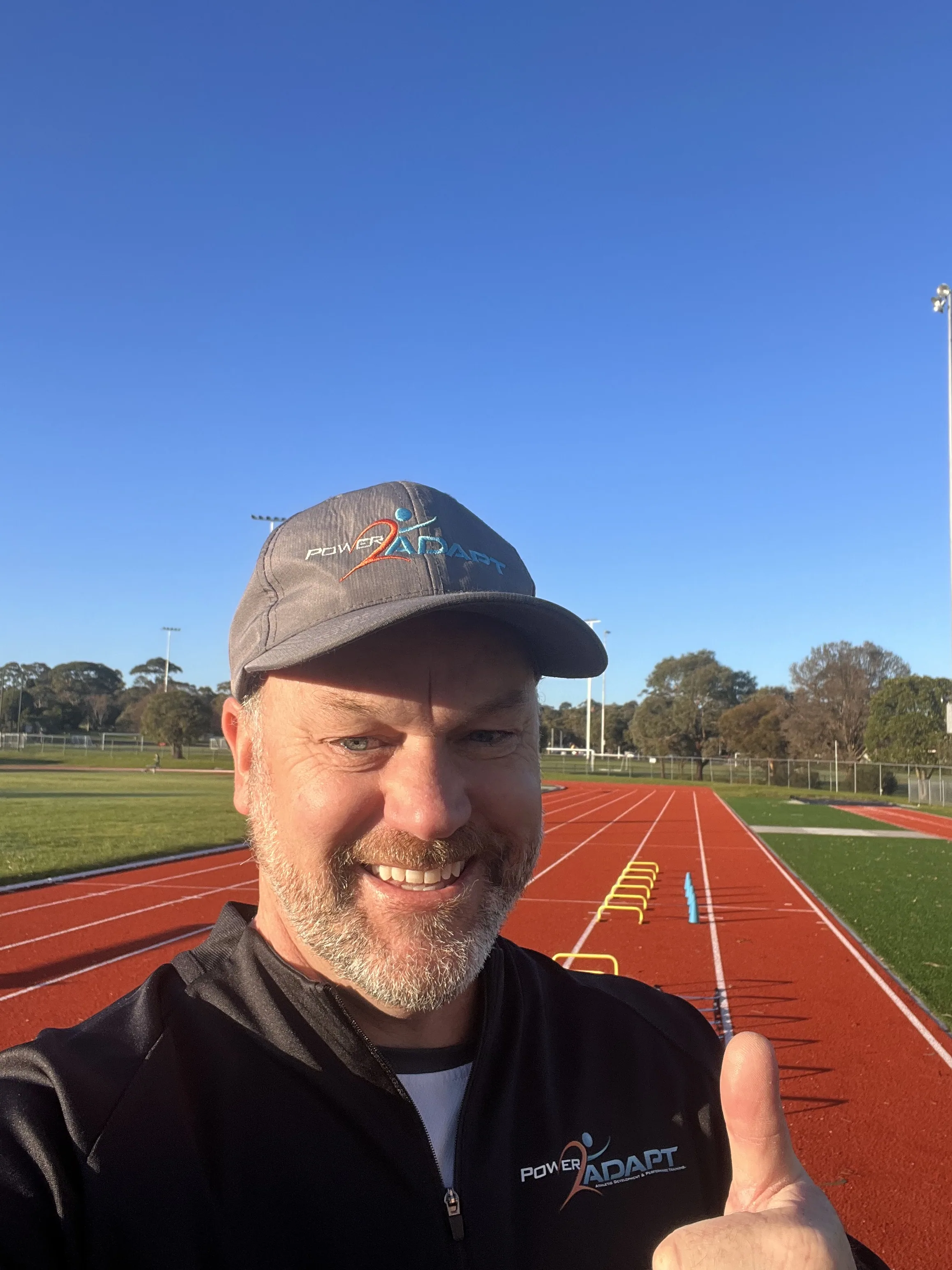Coach Al smiling at the athletics track in Power2ADAPT coaching kit